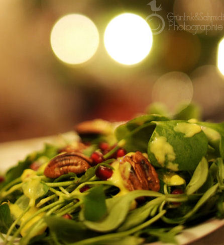 Green Salad garnished with roasted pecans, fresh pomegranate seeds and mango dressing